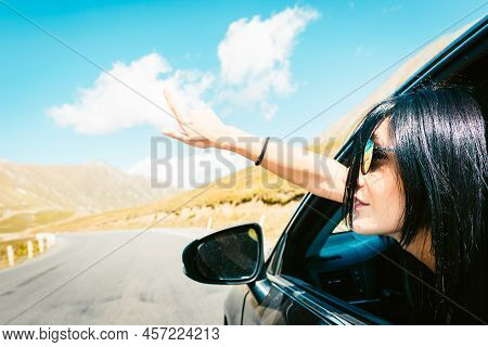 Female Caucasian Woman From Car Window Points Finger Up Left With Asphalt Road Background. Copypaste