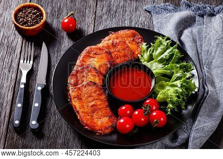 Grilled Slices Of Pork Loin Marinated In Paprika Based Sauce On Plate With Fresh Tomatoes And Lettuc
