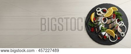 Slate Plate With Sliced Salted Herring Fillet, Parsley, Chili Pepper, Onion Rings And Lemon On Light