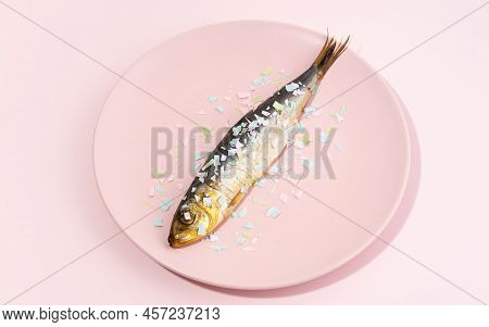 Fish Covered Microplastic On A Pink Plate. Impact Of Micro Plastic On The Food Chain. The Idea Of Mi