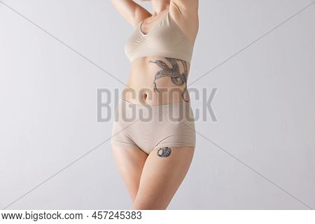 Cropped Image Of Slim Female Body In Beige Shapewear Underwear Isolated Over Grey Studio Background.