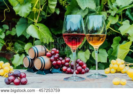 Winery Concept. Glasses Of White And Red Wine With Miniature Wine Barrels On The Wooden Table With G