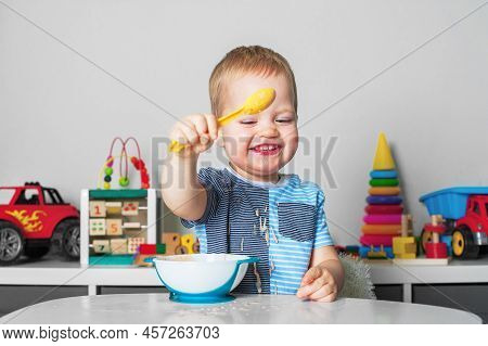Toddler Boy Eats With Spoon And Is Covered In Food. Baby Food, Food Allergies, Self-feeding....