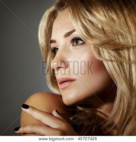 Closeup retrato de mulher loira sexy isolado no fundo cinza, penteado elegante, mak perfeito