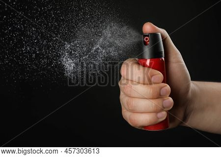 Man Using Pepper Spray On Black Background, Closeup