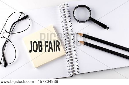 Word Job Fair On Sicker On The Notebook With Pencils,magnifier And Glasses