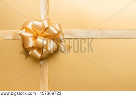 Top View Of Gold Ribbon Rolled And Yellowbow Isolated On Colored Background. Flat Lay With Copy Spac