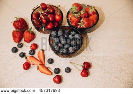 Fruits, Blueberries, Strawberries, Cherries, In Round Glass Plates On A Beige Table. View From Above
