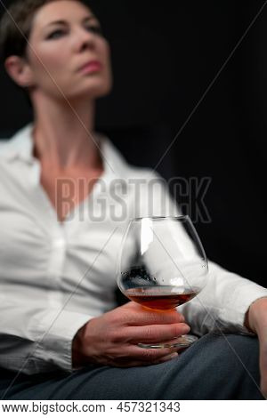 Drinking Glass Filled With Alcohol Held By Sad Looking Woman In Business Clothes Sitting With Her Le