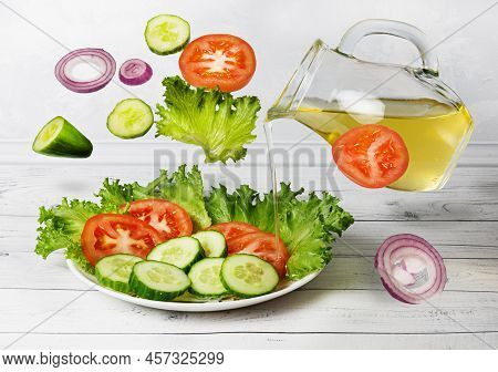 Vegetable Salad With Olive Oil In Levitation. Vegetable Salad Of Tomatoes, Cucumbers And Green Salad