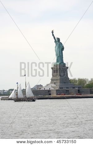 NEW YORK - 17 maggio: Una vela barca passa con la statua della libertà su 17 maggio 2013 a New York. La Stat