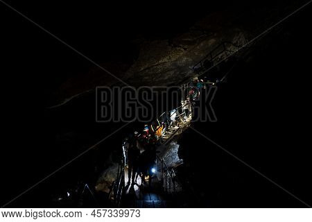 A Group Of People Climb The Stairs In Complete Darkness, The Light From The Lantern Illuminates The 