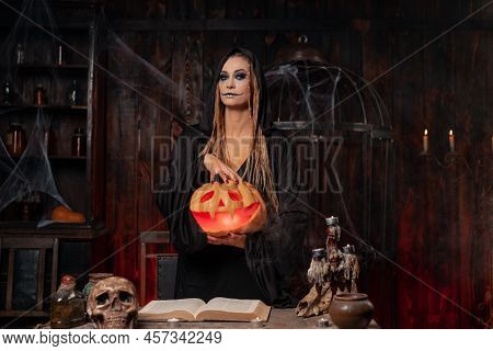 Halloween Concept. Black Witch Holding Halloween Pumpkin In Hand With Carved Smily Face In Hand Stan