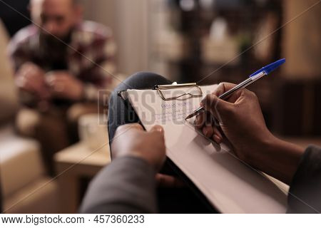 Male Psychologist Taking Notes At Couple Therapy Session To Help With Relationship Issues, Counselor