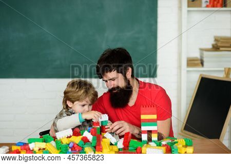 Father And Son Create Toys From Bricks. Dad And Kid Build Of Plastic Blocks. Daddy Takes Part In Gam