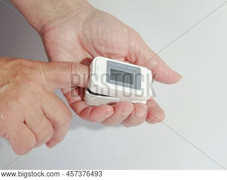 Woman Using Modern Fingertip Pulse Oximeter On Light Background, Closeup. Woman Hand With Fingertip 
