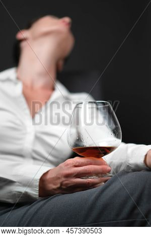 Drinking Glass Filled With Alcohol Held By Woman In Business Clothes Sitting With Her Legs Crossed A