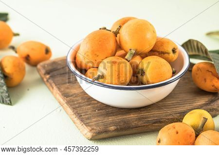 Ripe Medlar Fruit , Eriobotrya Japonica, And Green Medlar Leaves On Wooden Table. Top View