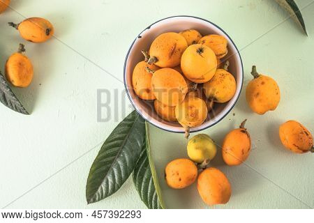 Ripe Medlar Fruit , Eriobotrya Japonica, And Green Medlar Leaves On Wooden Table. Top View