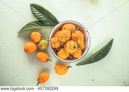 Ripe Medlar Fruit , Eriobotrya Japonica, And Green Medlar Leaves On Wooden Table. Top View