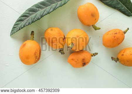 Ripe Medlar Fruit , Eriobotrya Japonica, And Green Medlar Leaves On Wooden Table. Top View