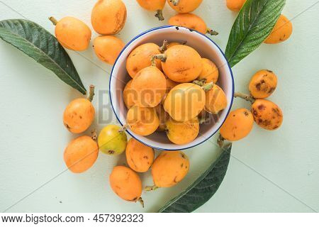 Ripe Medlar Fruit , Eriobotrya Japonica, And Green Medlar Leaves On Wooden Table. Top View