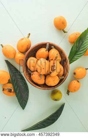 Ripe Medlar Fruit , Eriobotrya Japonica, And Green Medlar Leaves On Wooden Table. Top View