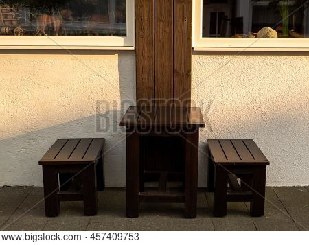 Wooden Stools And A Table Against The Wall.