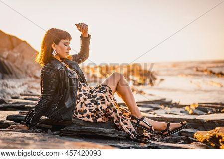 Summer Street Style On A Beach Next To Rocks Of A Young Brunette Caucasian Woman In A Leopard Dress 