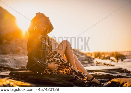 Summer Street Style On A Beach Next To Rocks Of A Young Brunette Caucasian Woman In A Leopard Dress 