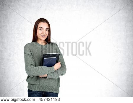Attractive Businesswoman Wearing Casual Wear Is Standing Holding Notebook Near Empty White Wall In B