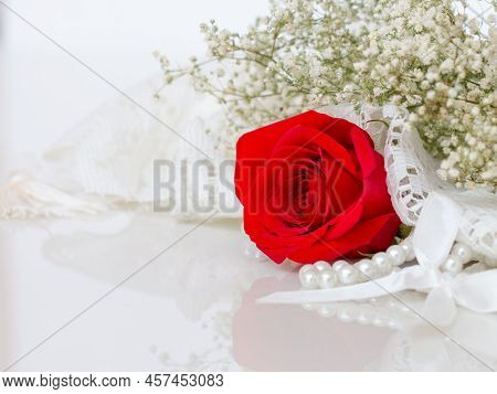 Close Up Of Red Rose On White Lace And Pearls Dedorated Around.