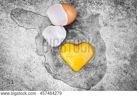 Heart Shape Egg Yolk With Eggshells On The Ground. Concept Valentines Day