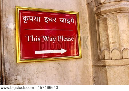 Red Sign Board Hanging On The Wall. Sign Says This Way Please. Sign Board In Hindi And English Showi