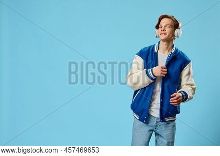 A Stylish Young Man In A Fashionable Jacket And With Large White Headphones On His Head Dances To Th