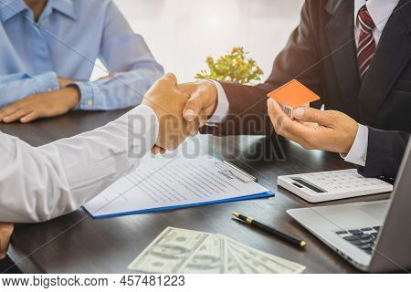 Real Estate Agents Shaking Hands To Congratulate Buyers After Giving Buyers A Purchase Contract, A C