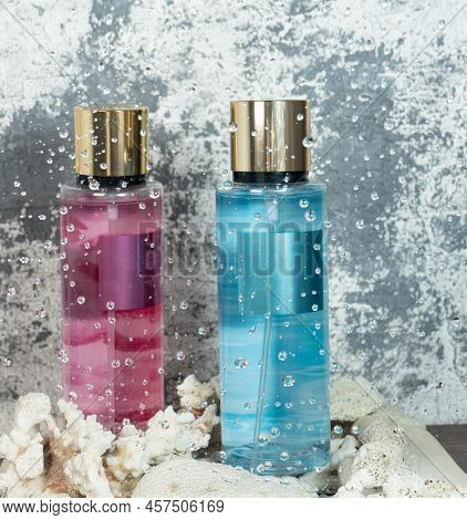 Two Bottles Of Cologne For The Woman's Body. One Bottle Is Pink And The Other Is Light Blue. In Fron