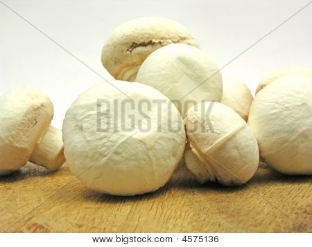 weiße Pilze auf einer hölzernen Platte, braun