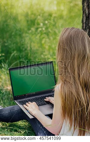 Girl Sits On The Grass And Works At A Laptop. Freelance. Selfeducation. The Concept Of Distance Lear