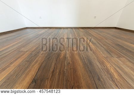 Laminated Wood Floor With White Wall. Empty Room With Floating Laminate In New Apartmen