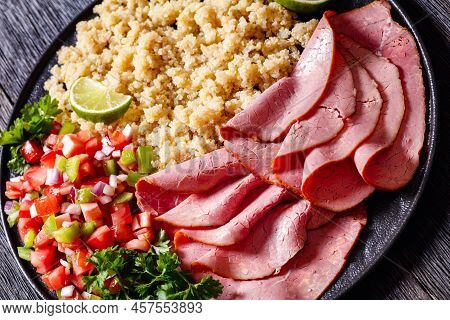Thinly Sliced Roast Beef Fillet With Quinoa And Tomato Pepper Salsa On Black Plate, Close-up