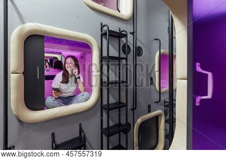 Young Woman With Gadgets In Modern Look Capsule Hotel