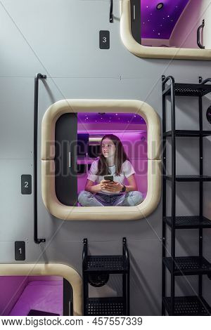 Young Woman With Gadgets In Modern Look Capsule Hotel
