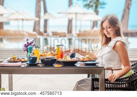 Woman On Breakfast Near Swimming Pool In Luxurious Tropical Resort. Table Full Of Various Food And D