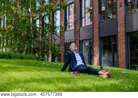 Mature Businessman Resting And Sitting Barefoot In Park, Feeling Free, Escaping From Work, Work Life