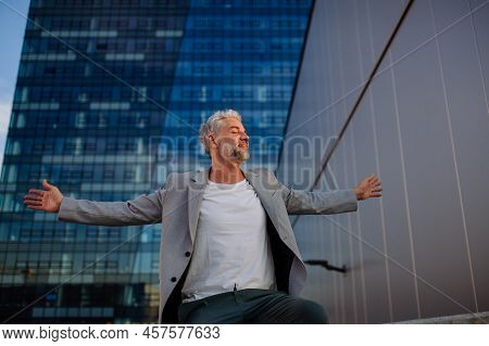 Portrait Of Happy Energetic Mature Businessman With Arms Outstretched Balancing On Wall , Feeling Fr