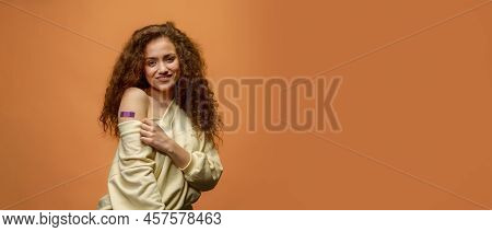 Portrait Of A Female Smiling After Getting A Vaccine. Woman Holding Down Her Shirt Sleeve And Showin