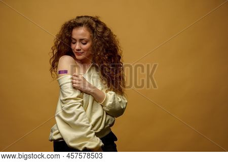 Portrait Of A Female Smiling After Getting A Vaccine. Woman Holding Down Her Shirt Sleeve And Showin