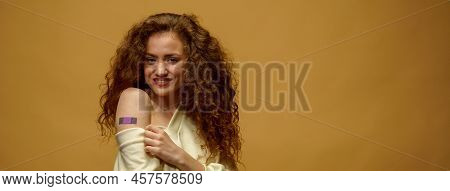 Portrait Of A Female Smiling After Getting A Vaccine. Woman Holding Down Her Shirt Sleeve And Showin