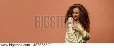 Portrait Of A Female Smiling After Getting A Vaccine. Woman Holding Down Her Shirt Sleeve And Showin